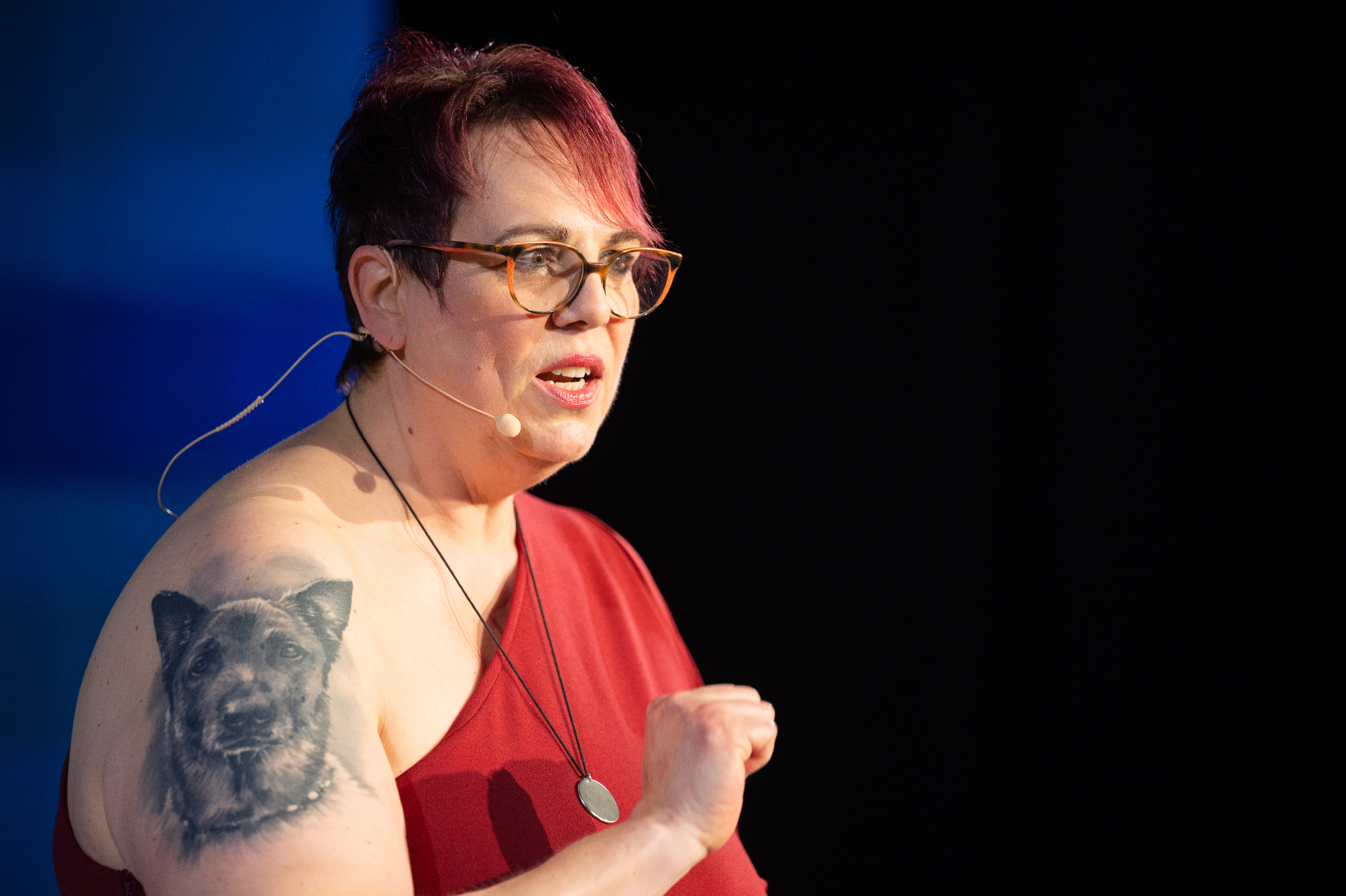 Nicole Frontzek im roten Kleid mit Mikrofon und sichtbarem Tattoo